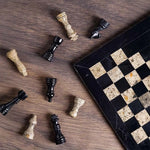 Black and fossil coral marble chess set 12 inch — pieces scattered on dark wood surface showing white marble and green onyx stone detail by RADICALn