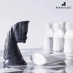 Black marble antique knight chess figure close-up — hand-carved medieval horse form with white marble pawns on board by RADICALn