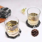 Black octagon marble coasters under two whiskey glasses on a white table