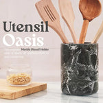 Black marble crock for utensils holding wooden spatulas on a kitchen countertop