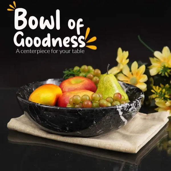 Black marble fruit bowl filled with apples, grapes and a pear as a table centerpiece