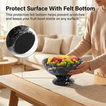 Black marble pedestal fruit bowl with a protective felt bottom shown in a close-up, held above a wooden table