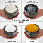 Black marble bowl held in hand holding shaving foam, jewellery, paper clips and spices