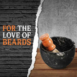 Black marble shaving bowl holding a wooden shaving brush on a wood counter