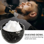 Black marble shaving bowl full of lather with a barbershop shave in the background