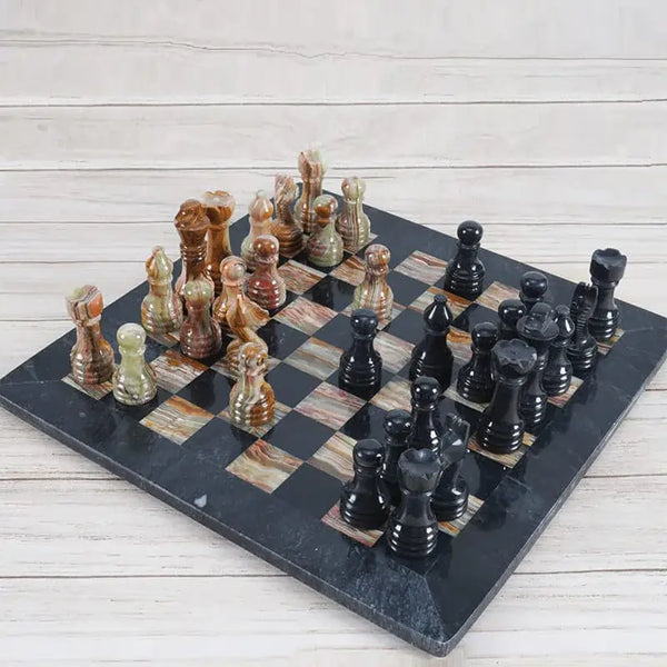 Black and multi green onyx marble chess set 15 inch — all 32 pieces in starting position on wood surface by RADICALn