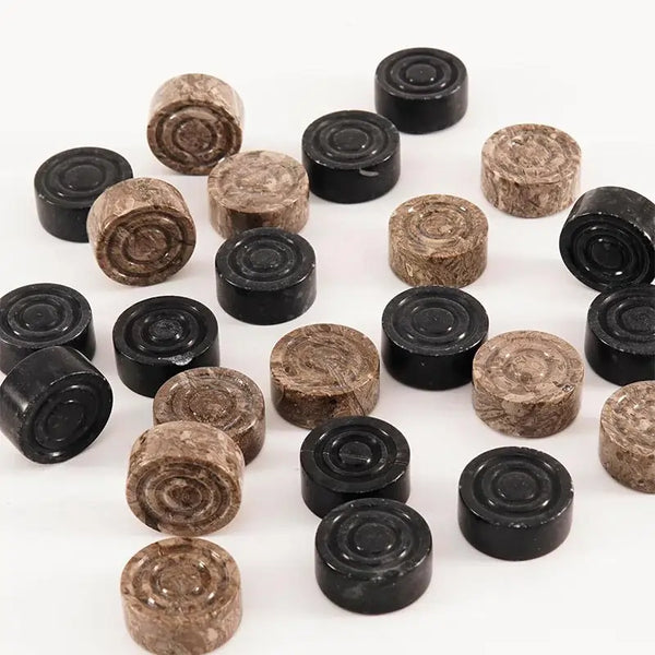 Black and oceanic marble checkers discs scattered on white surface — concentric ring and felt bottom detail by RADICALn