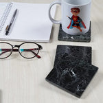 Black square marble coasters on a desk with a printed mug, notebook and glasses