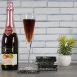 Stacked black square marble coasters beside a champagne flute and sparkling drink bottle