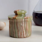 Handmade green onyx marble butter keeper with domed lid on a kitchen counter beside eggs