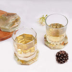 Green onyx octagon marble coasters under two whiskey glasses on a white table