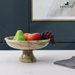 Green onyx marble footed fruit bowl on a pedestal base holding an apple, bananas and grapes