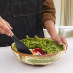 Green onyx marble bowl holding a fresh salad being tossed with a serving spoon
