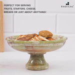 Green onyx marble pedestal bowl raised on a stem holding sliced bread and rolls