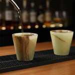 Drink poured into a green onyx marble shot glass on a bar mat