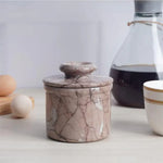 Handmade marinara marble butter keeper with domed lid on a kitchen counter beside eggs