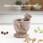 Marinara marble mortar and pestle on a kitchen counter with whole peppercorns, cardamom pods and fresh coriander