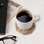Natural brown octagon marble coaster under a white coffee cup beside a newspaper and glasses