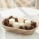 Oval natural brown marble dough bowl used as a candle centerpiece with pillar candles and pinecones