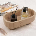 Natural brown oval marble trinket dish holding a reed diffuser and perfume beside books