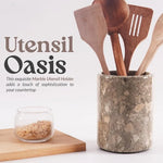 Oceanic marble crock for utensils holding wooden spatulas on a kitchen countertop