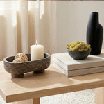 Oceanic marble footed bowl with a candle and rattan balls on a wooden coffee table