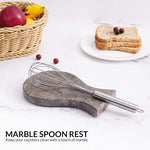Oceanic marble spoon rest holding a whisk on a kitchen counter with fruit and toast