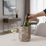 Hand lowering a wine bottle into a oceanic hexagon marble wine cooler on a table