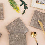 Oceanic square marble coasters styled with gold cutlery and greenery on a pink surface