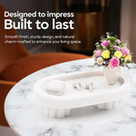 Raised white marble tray on fluted legs holding earbuds and a vase on a side table