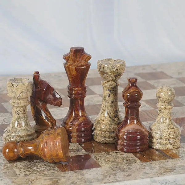 Red marble and fossil coral chess pieces scattered on board — warm toned natural stone figures by RADICALn