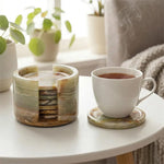 Round green onyx marble coaster set and holder on a coffee table with a cup of tea