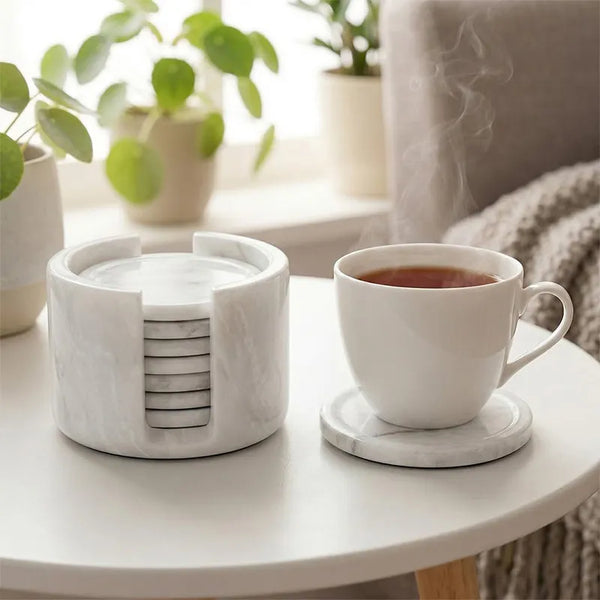 Round white marble coaster set and holder on a coffee table with a cup of tea