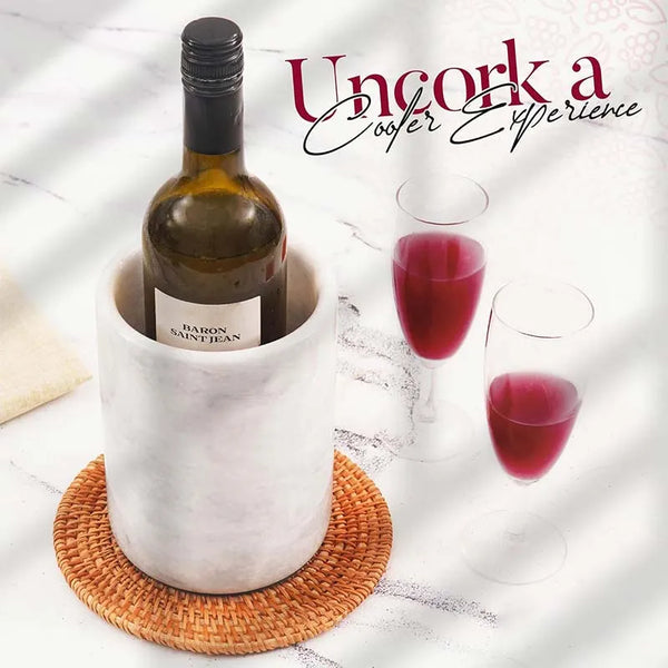Round white marble wine cooler on a rattan coaster with two glasses of red wine