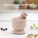 Verona marble mortar and pestle on a kitchen counter with whole peppercorns, cardamom pods and fresh coriander