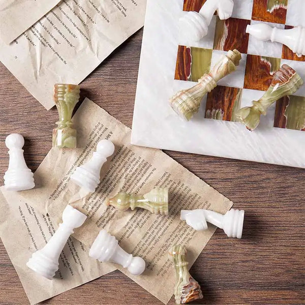 White marble and green onyx chess pieces scattered on book pages — board corner detail by RADICALn