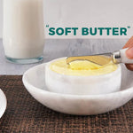 Close-up of soft spreadable butter in a white marble butter dish with a marble-handled knife