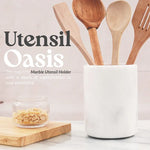 White marble crock for utensils holding wooden spatulas on a kitchen countertop