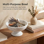 White marble pedestal bowl used as an entryway key holder with car keys and dried flowers on a console table