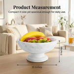 White marble pedestal fruit bowl measuring 10 inches wide and 5 inches tall, holding fruit on a coffee table