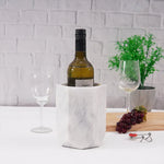 White marble hexagon wine cooler chilling a bottle beside a glass and grapes