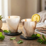 Pair of white onyx marble shot glasses garnished with lemon and mint on wood