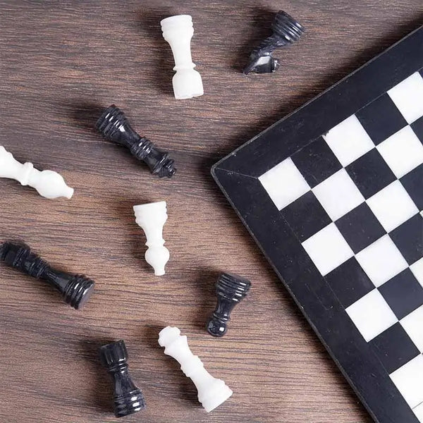 Black and white marble chess set 12 inch — pieces scattered on dark wood surface showing black and white marble stone detail by RADICALn
