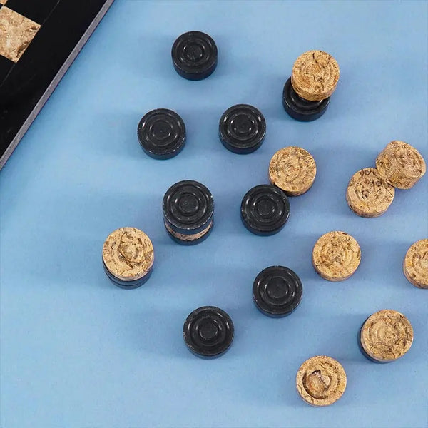 Black and fossil coral marble checkers discs scattered on blue surface — concentric ring and felt bottom detail by RADICALn