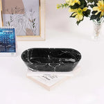 Black marble oval tray on a desk with books, a calendar and flowers