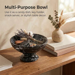 Black marble pedestal bowl used as an entryway key holder with car keys and dried flowers on a console table
