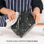 Hands wiping a black marble utensil crock, showing its smooth easy-to-clean surface
