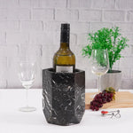 Black marble hexagon wine cooler chilling a bottle beside a glass and grapes