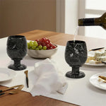 Red wine poured into a black marble wine glass at a set dinner table