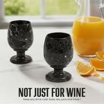 Pair of black marble wine glasses beside an orange juice pitcher for any cold drink